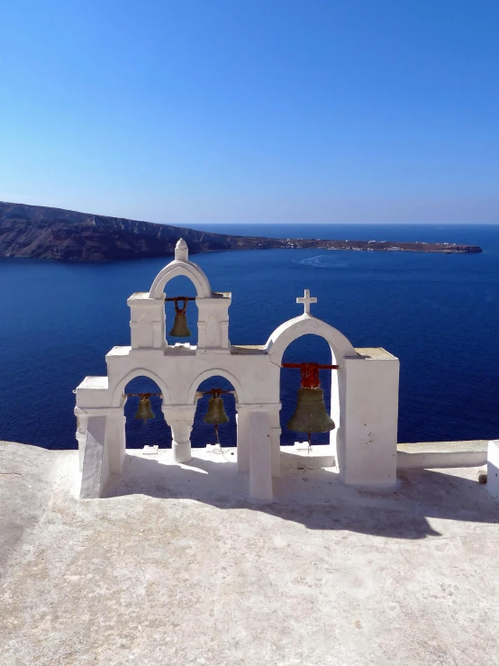 a white church with bells overlooking the ocean