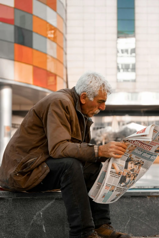 a man sitting on a bench reading a newspaper