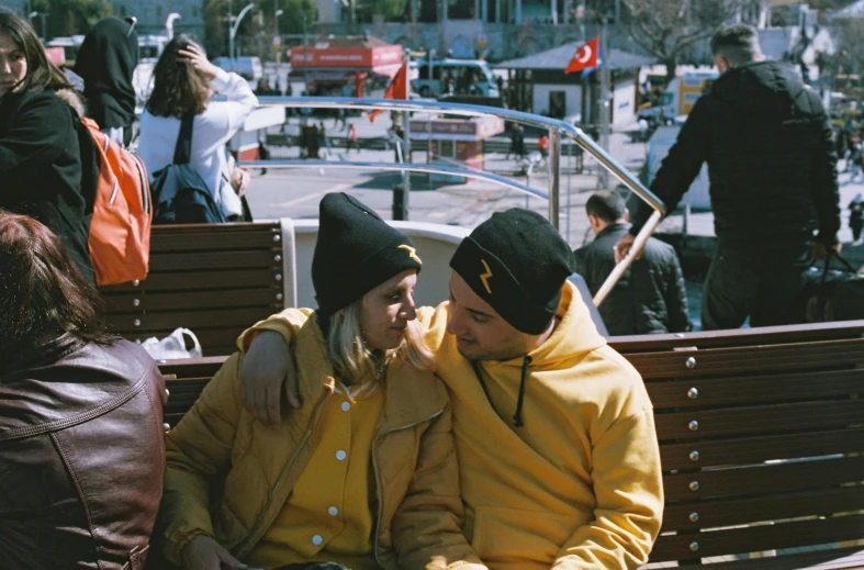 two people in hats sitting on a bench together