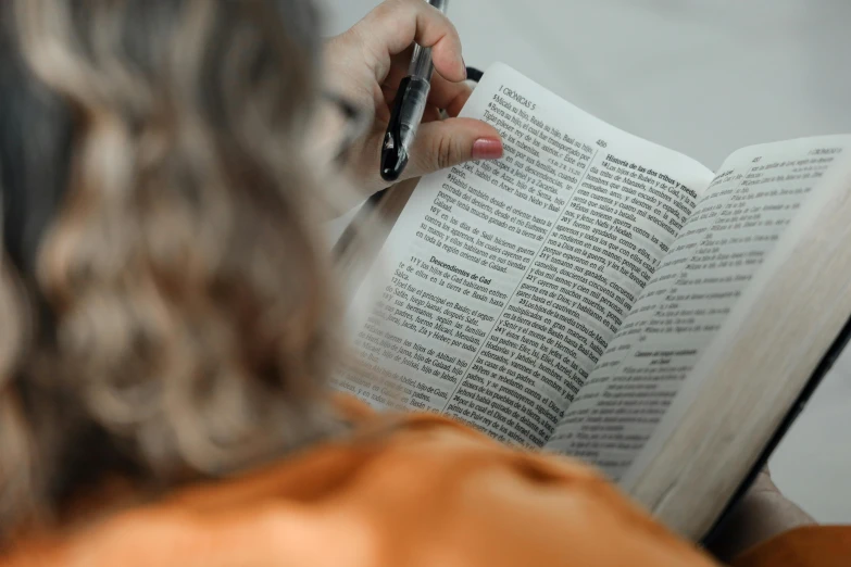 a woman in orange jacket holding an open book