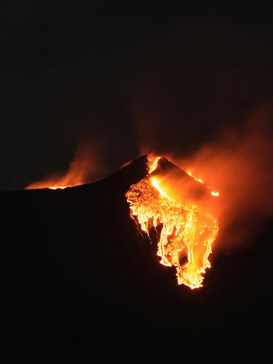 a bright orange and yellow flame pouring out of the volcano