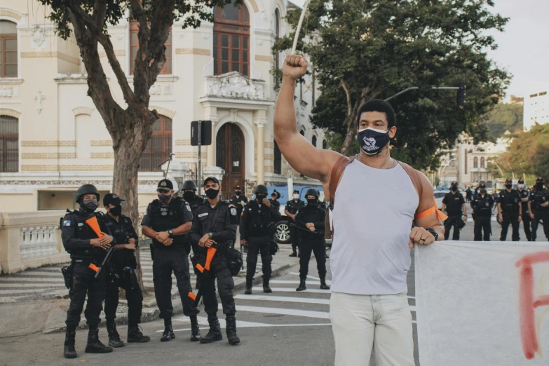 a protester holds his fist up in the air while a group of protesters stand behind him