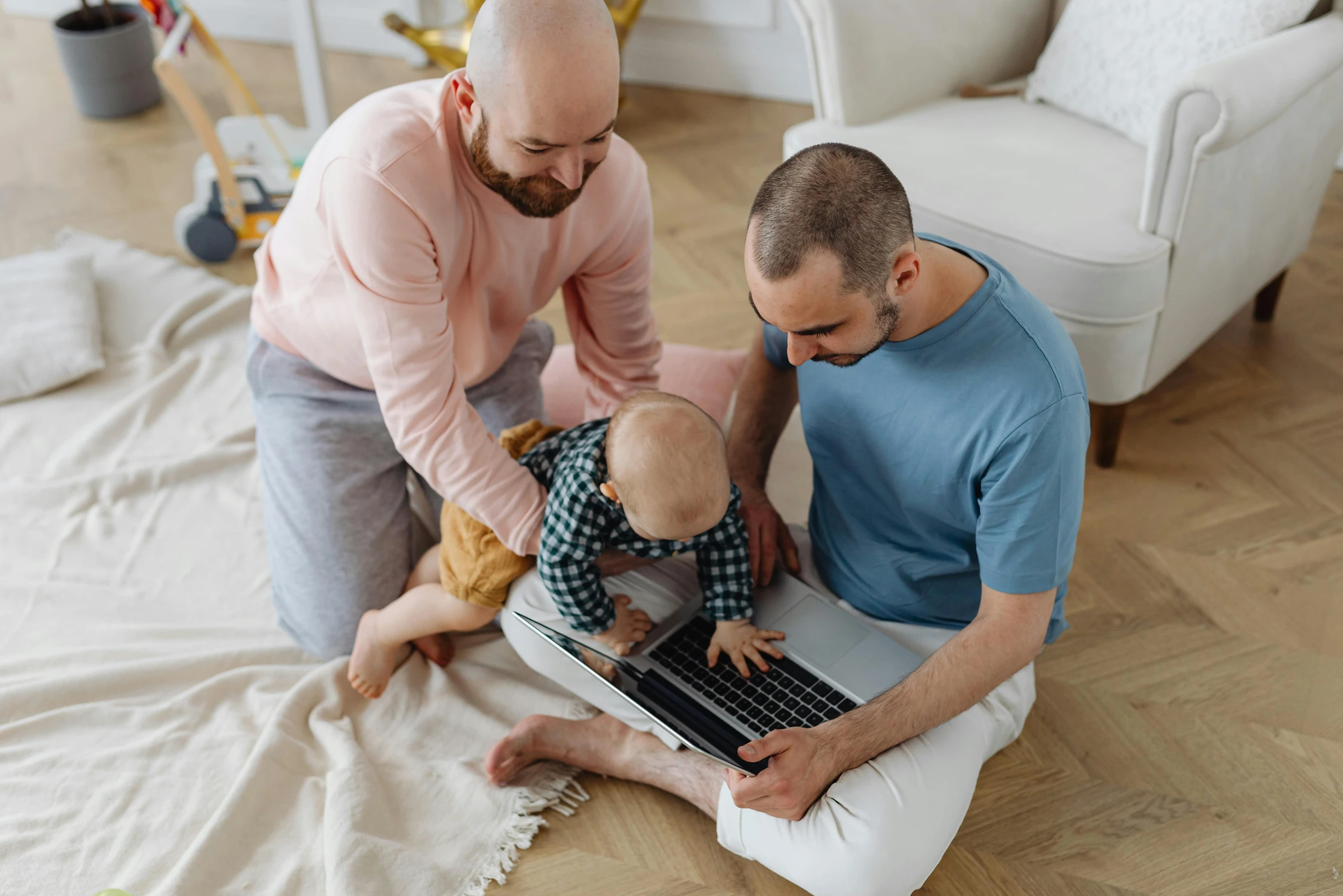 a man and a young baby play with a laptop on a floor