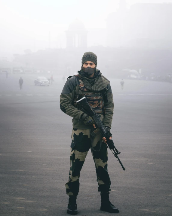 a man in camouflage stands with a gun