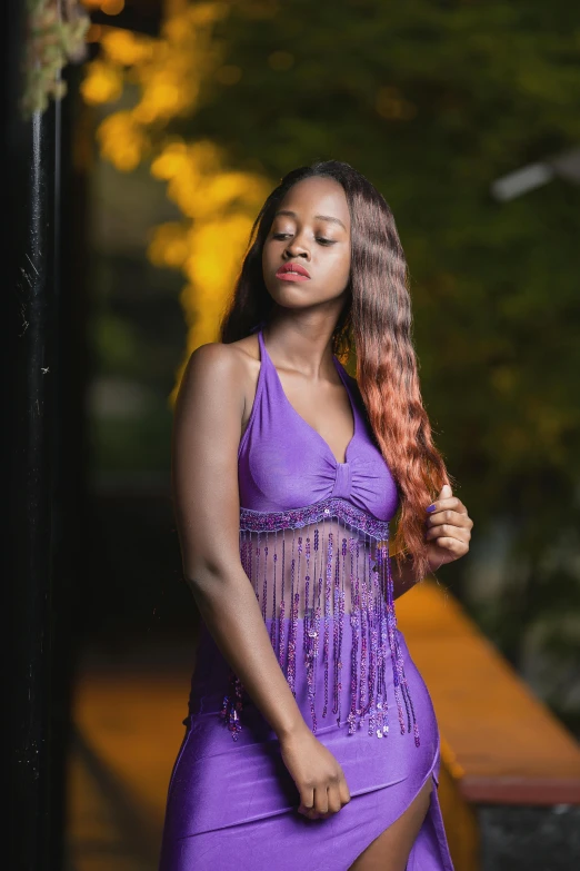 a woman with long, curly hair is dressed in a purple dress and posing for a picture