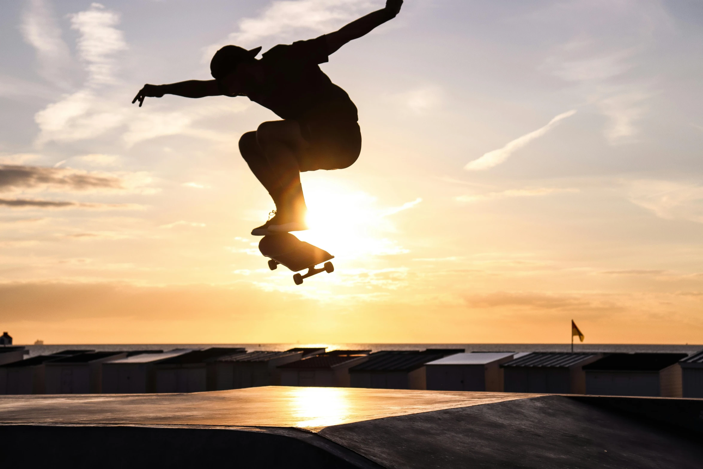 a person jumping a skate board into the air at sunset