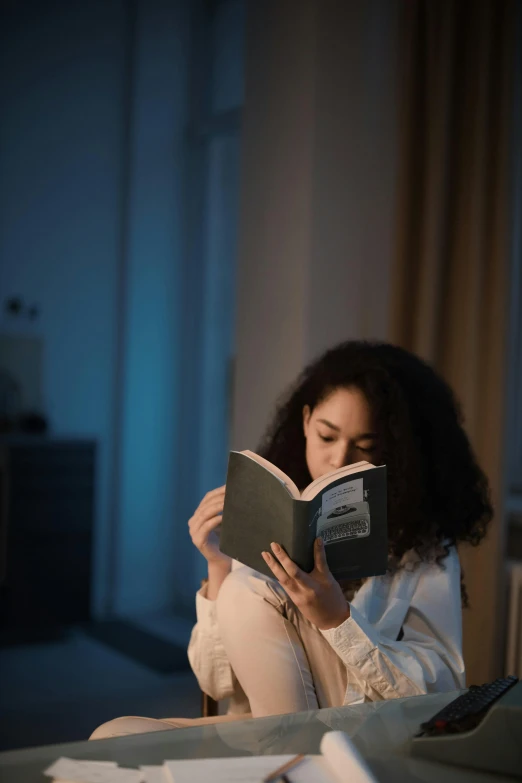 a woman sitting at her desk while reading a book