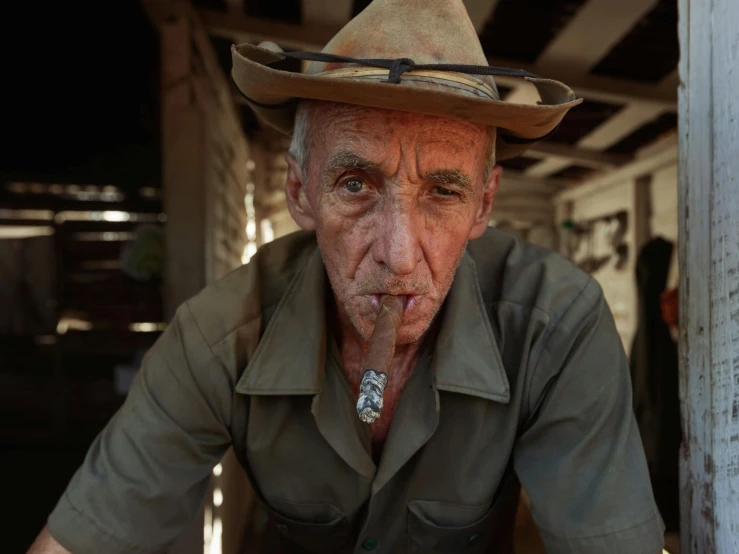 an old man wearing a fedora with a cigarette in his mouth