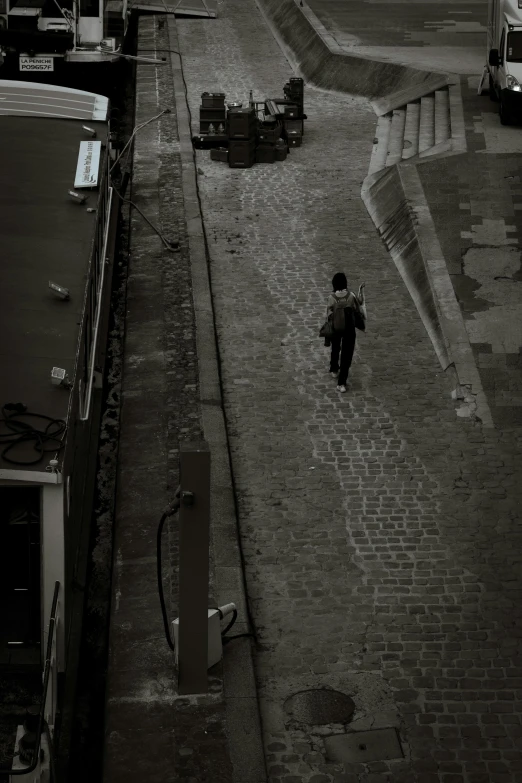 a man walking on a cobble street next to parked cars