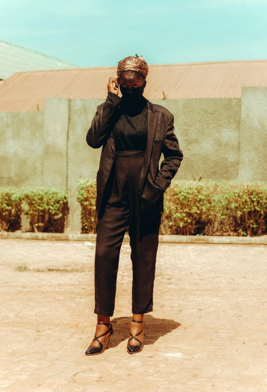 an african woman wearing dark colored clothing talking on her cell phone