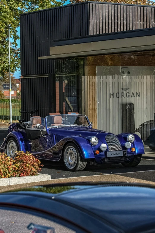 a blue sports car parked in front of a black building