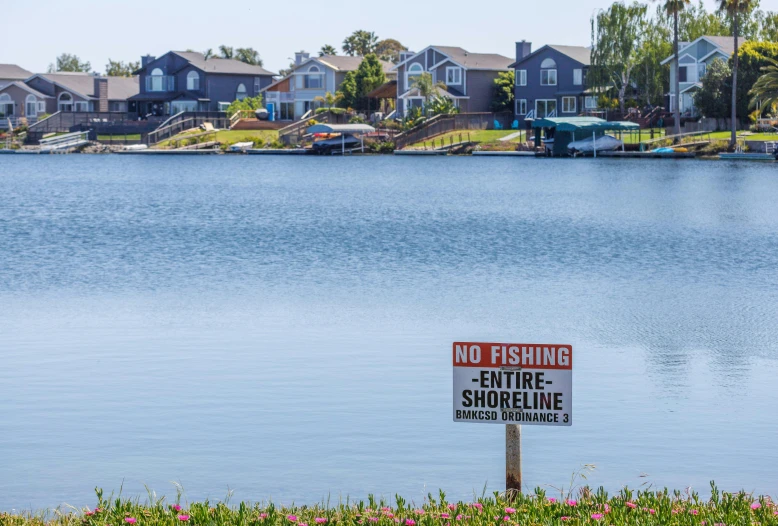 an old sign is next to a lake