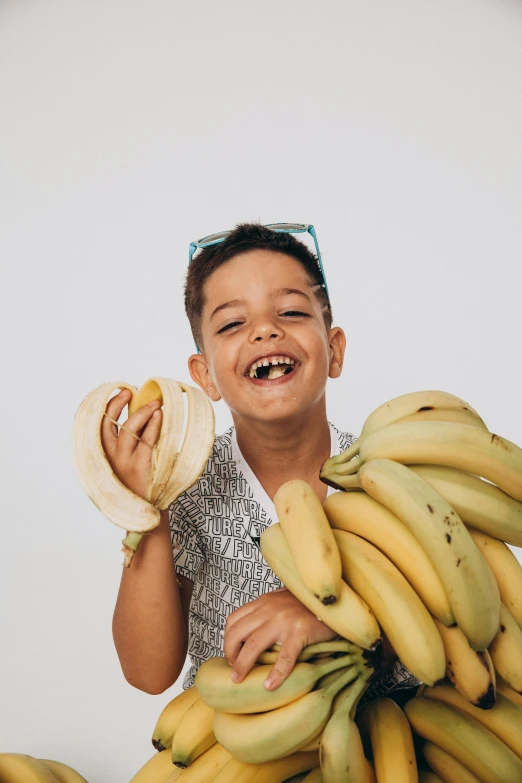 a smiling boy holding bananas and wearing sunglasses