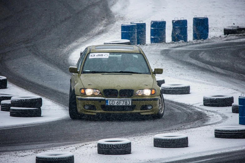 yellow car driving on snowy road surrounded by tires