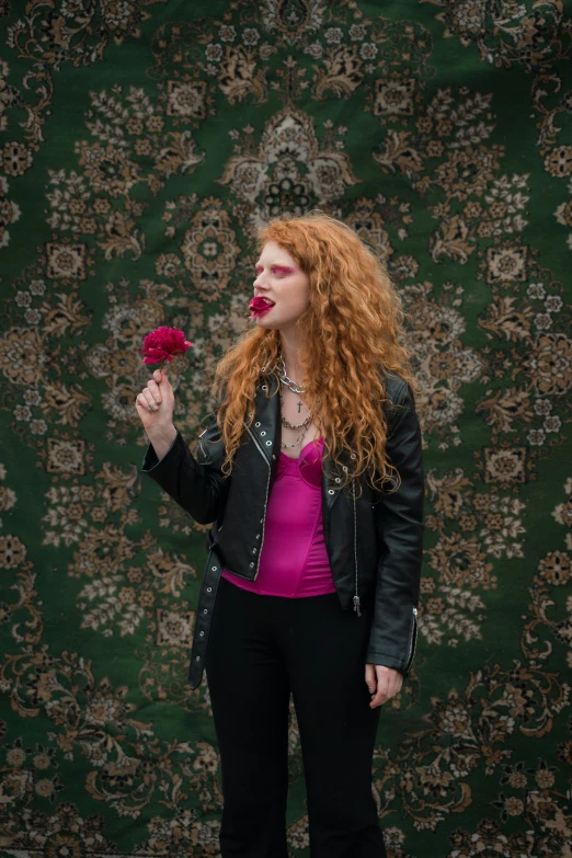 a woman with red hair is holding a flower