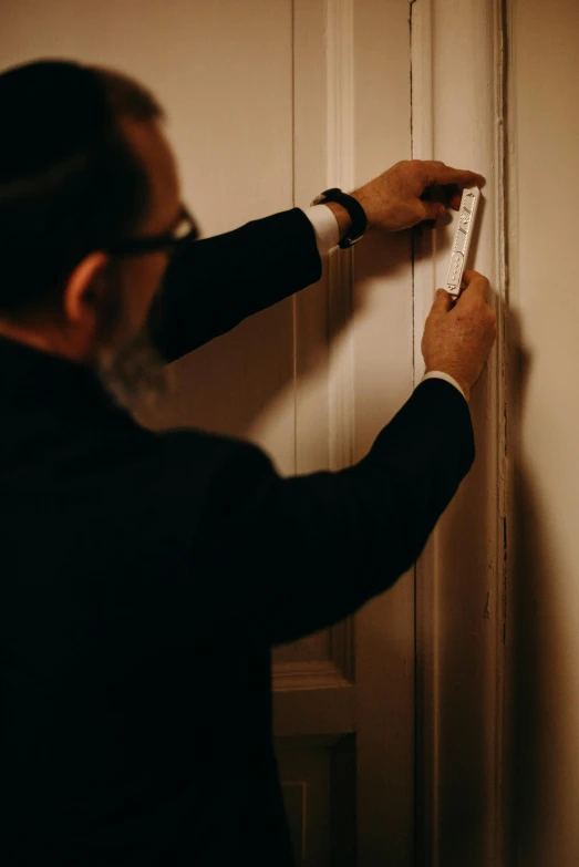 a person in a black suit is looking at soing on the wall