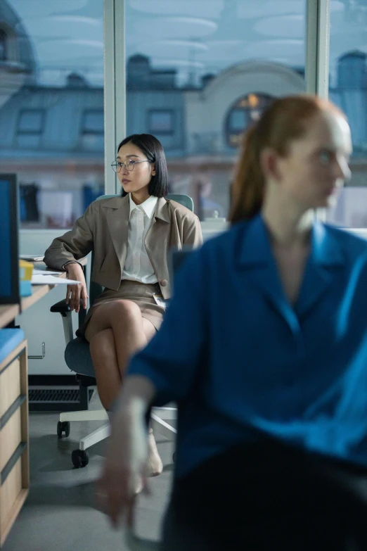 two women sit in chairs in an office