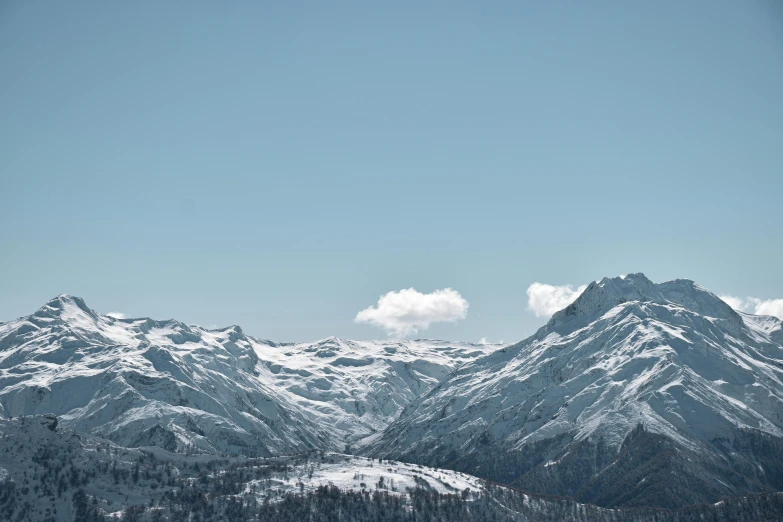 the mountain side is covered in snow and has two skiers on it