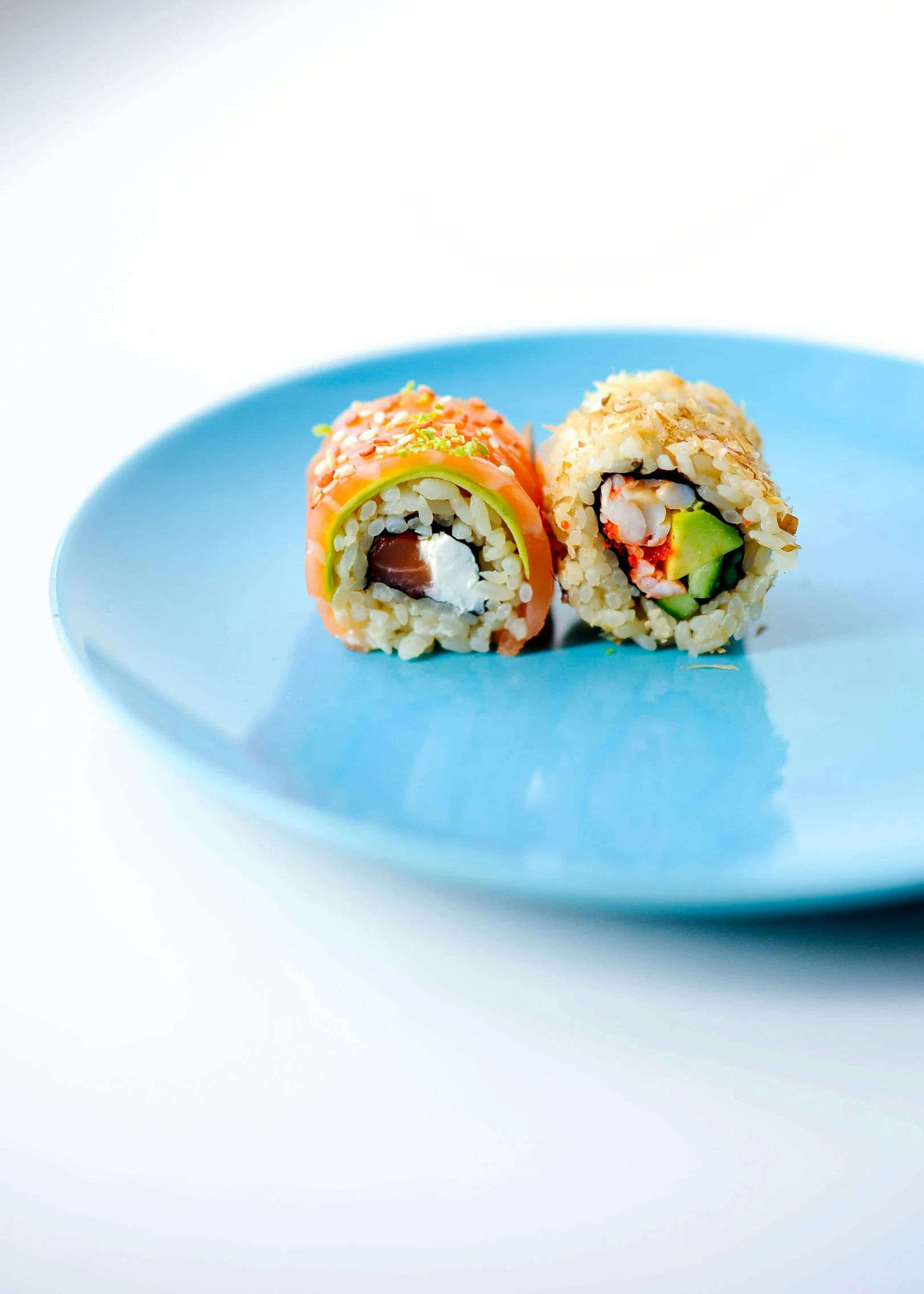 sushi on a blue plate with cucumber and carrot