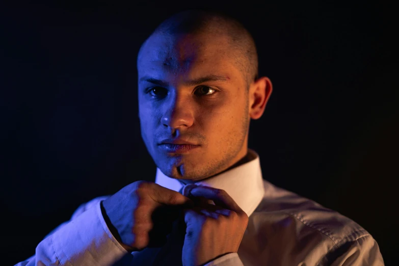 a young man adjusting his tie in the dark