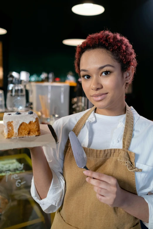 a woman holding up a piece of cake on a tray