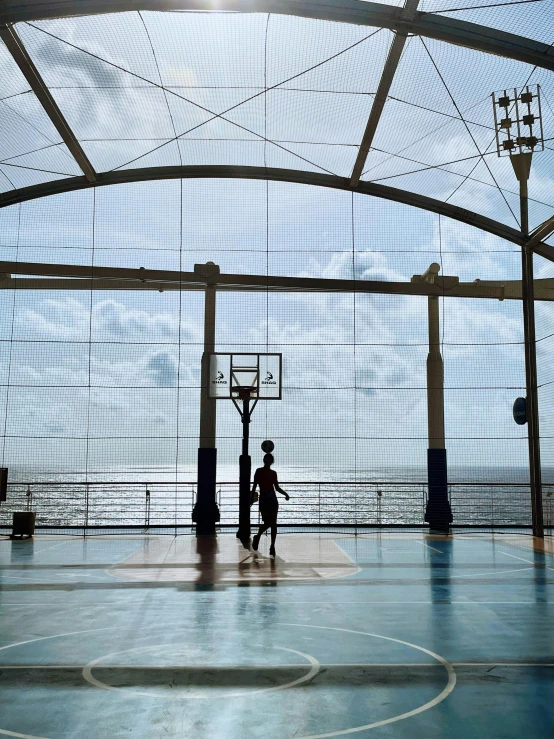 three men play basketball on a tennis court under an indoor structure