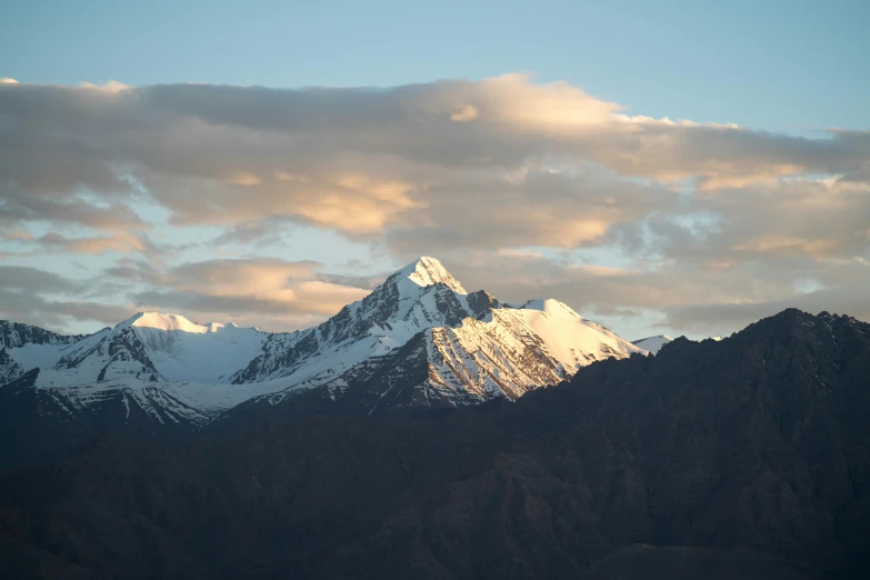 a mountain with snow and clouds in the background