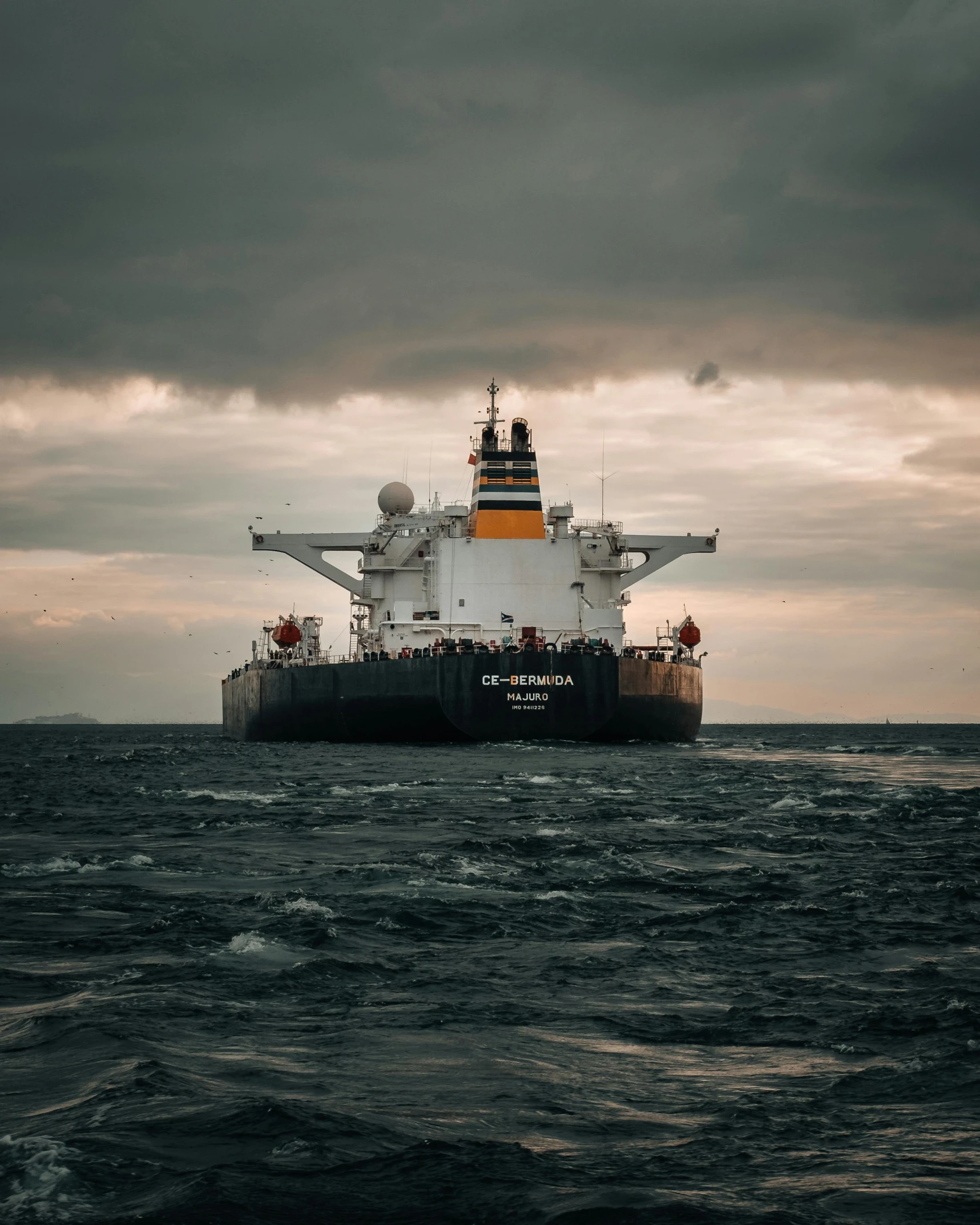 a ship floating on the ocean next to a gray and cloudy sky