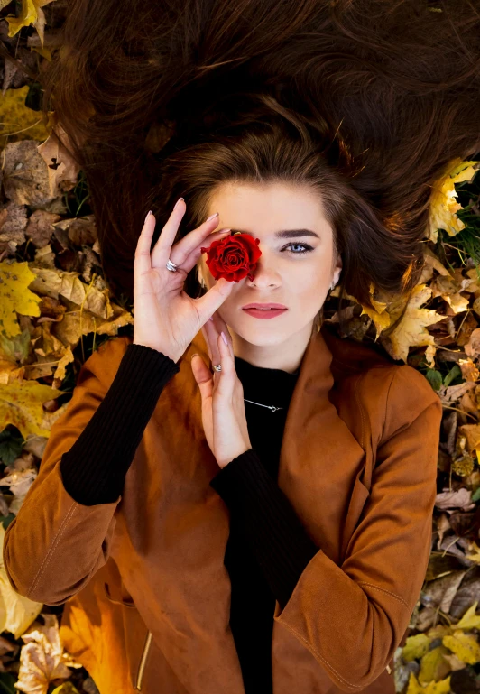 an overhead view of a young lady covering her eyes and a rose in her hand