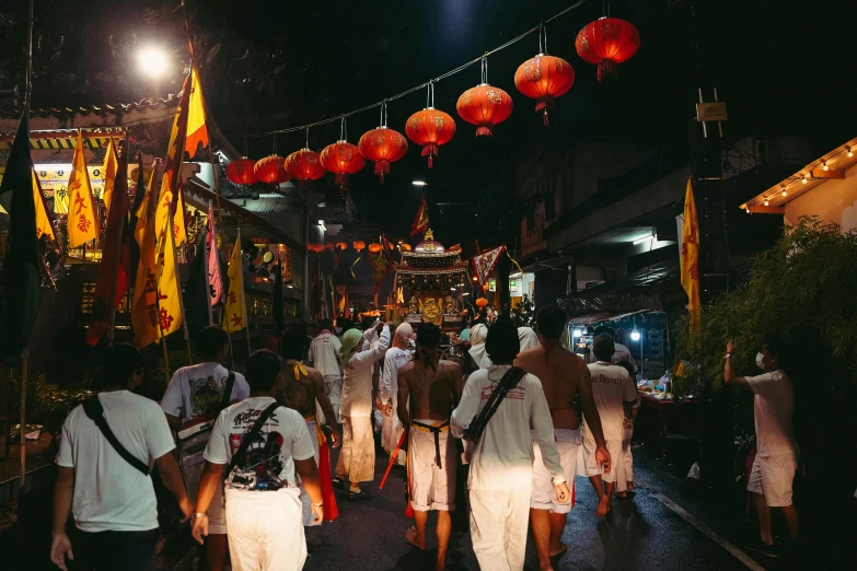 people walking on the street with red lanterns strung over them