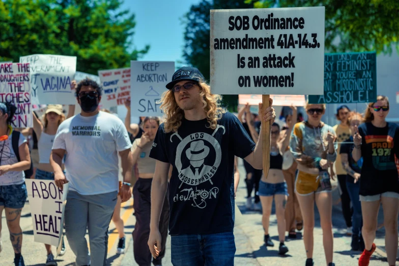 a man with a sign in his hand stands among protesters