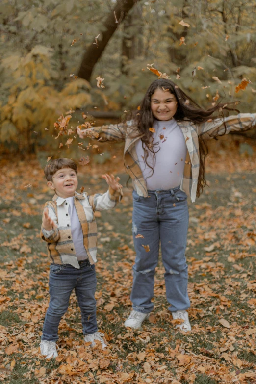 a woman and a little boy standing next to each other in leaves