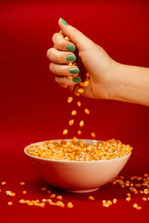 a woman's hand adding corn to a bowl