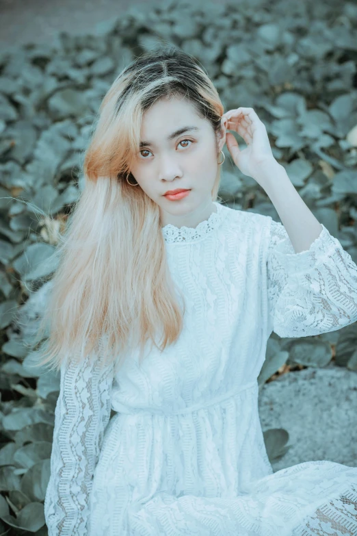 a woman in a white dress is sitting on a rock