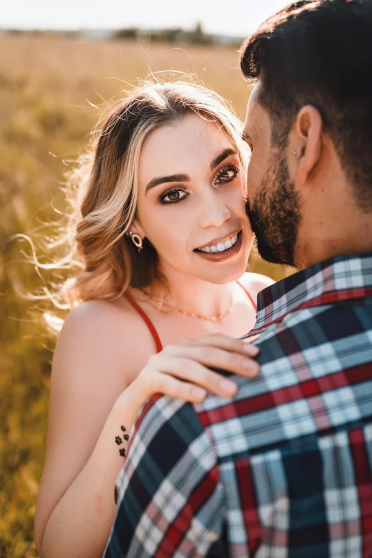 a woman holding onto the forehead of a man in a field