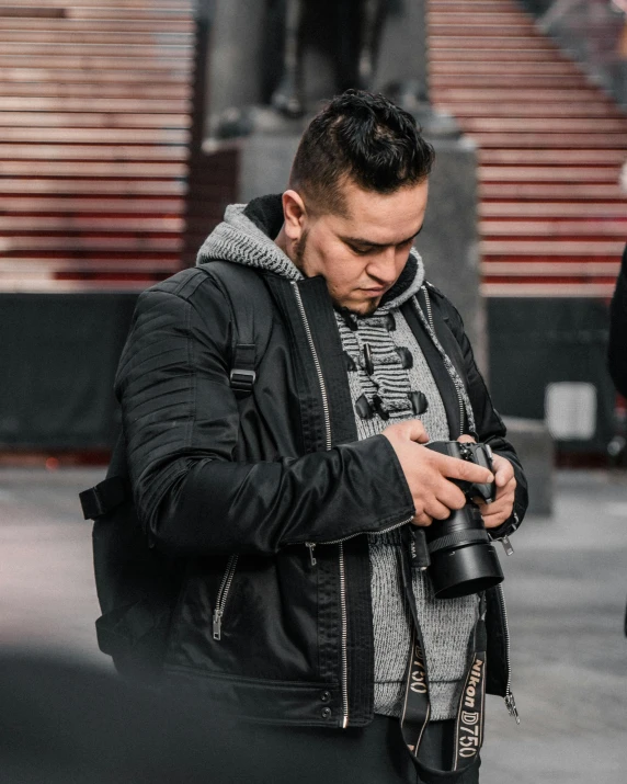 man in black jacket checking his cell phone outside