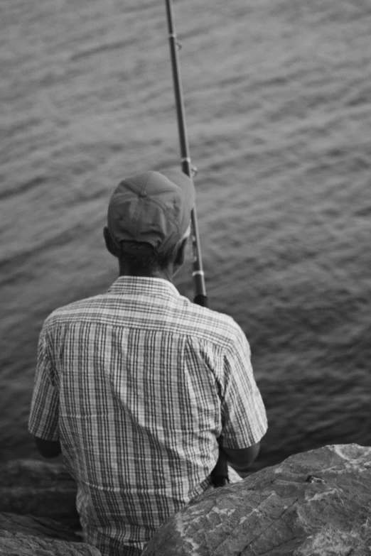 man fishing in the water from the rocks at a beach