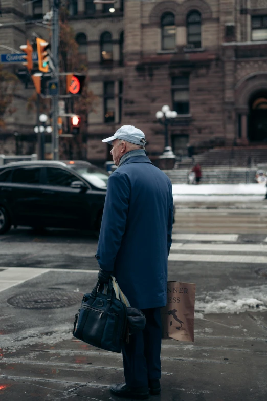 a man holding his bags waiting to cross the street