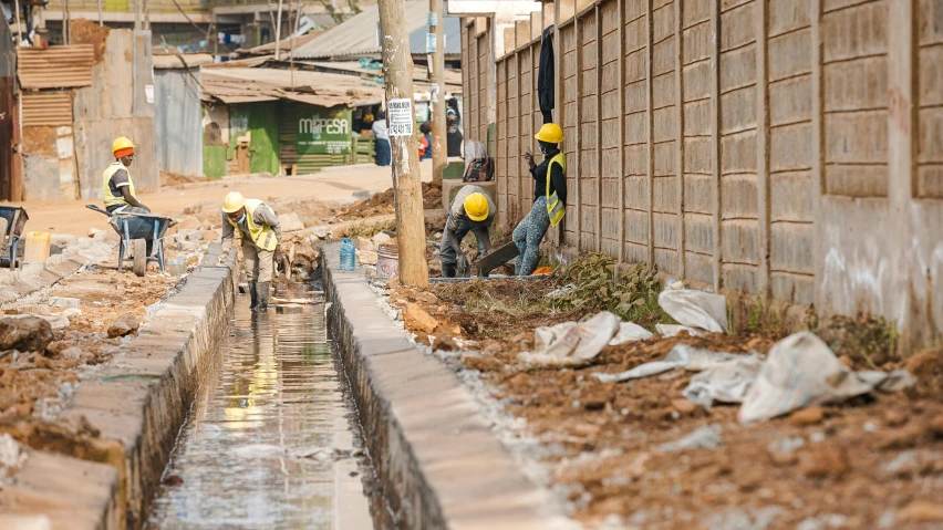 people with hard hats and construction machinery cleaning the sidewalk