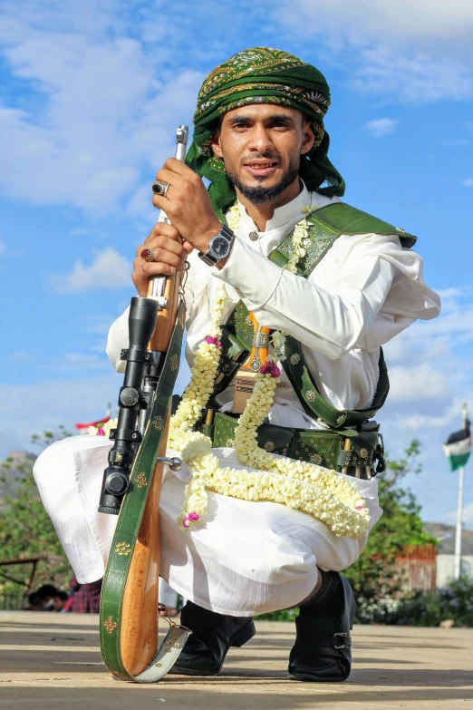 man dressed up in traditional attire with rifle and flower wreath