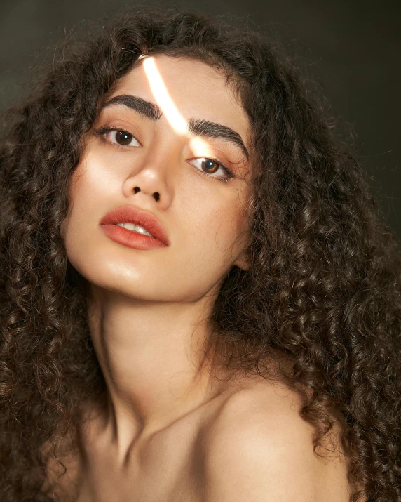 a woman with curly hair and a light shining behind her