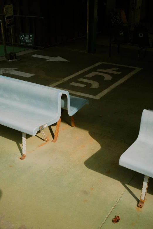 a couple of white benches sit in a parking lot