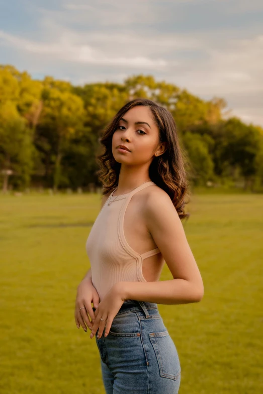 a woman in a beige tank top is posing for the camera