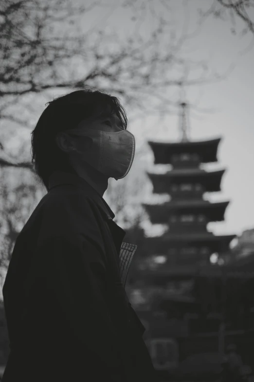 a man is outside looking away at a building in the background