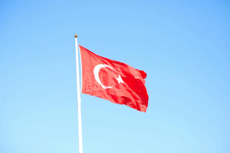 a flag of the country of turkey flies in a clear sky