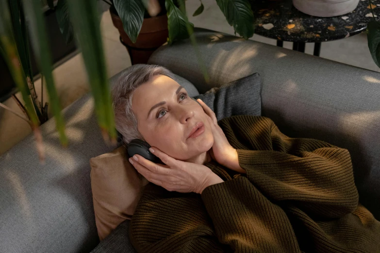 an elderly woman laying on a couch talking on a cellphone