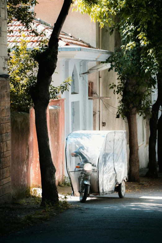 a scooter covered with a tarp sitting under a tree