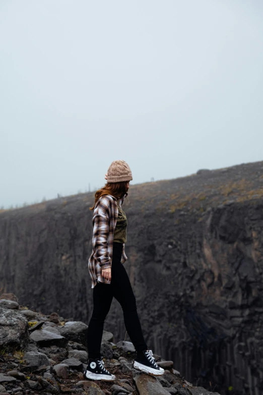 a person standing on a rock with their hand in the pocket