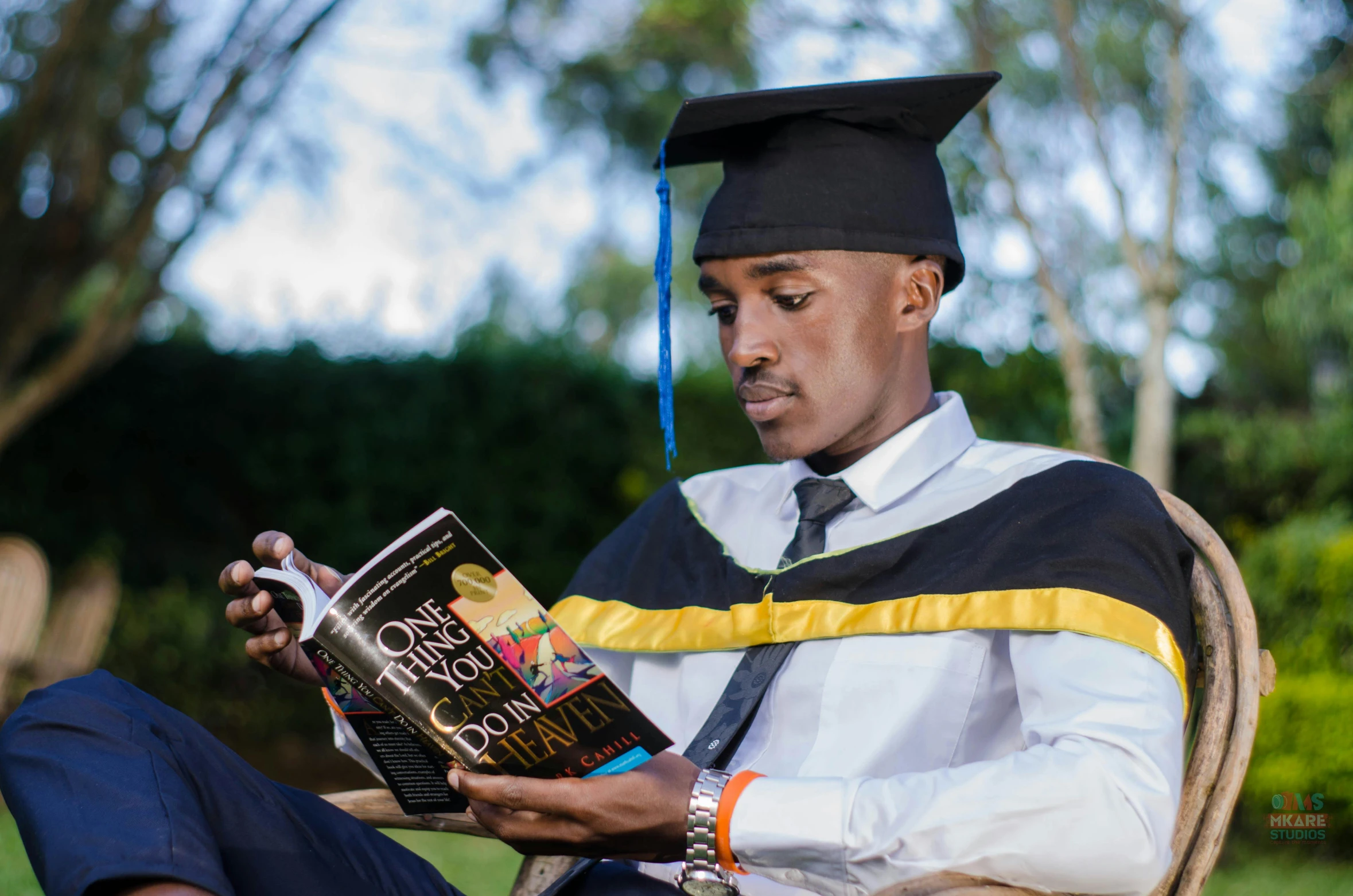 a person in a graduation cap and gown reading a book