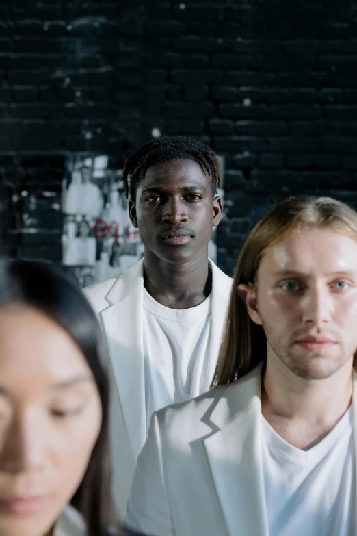 a young man with long hair is surrounded by his peers